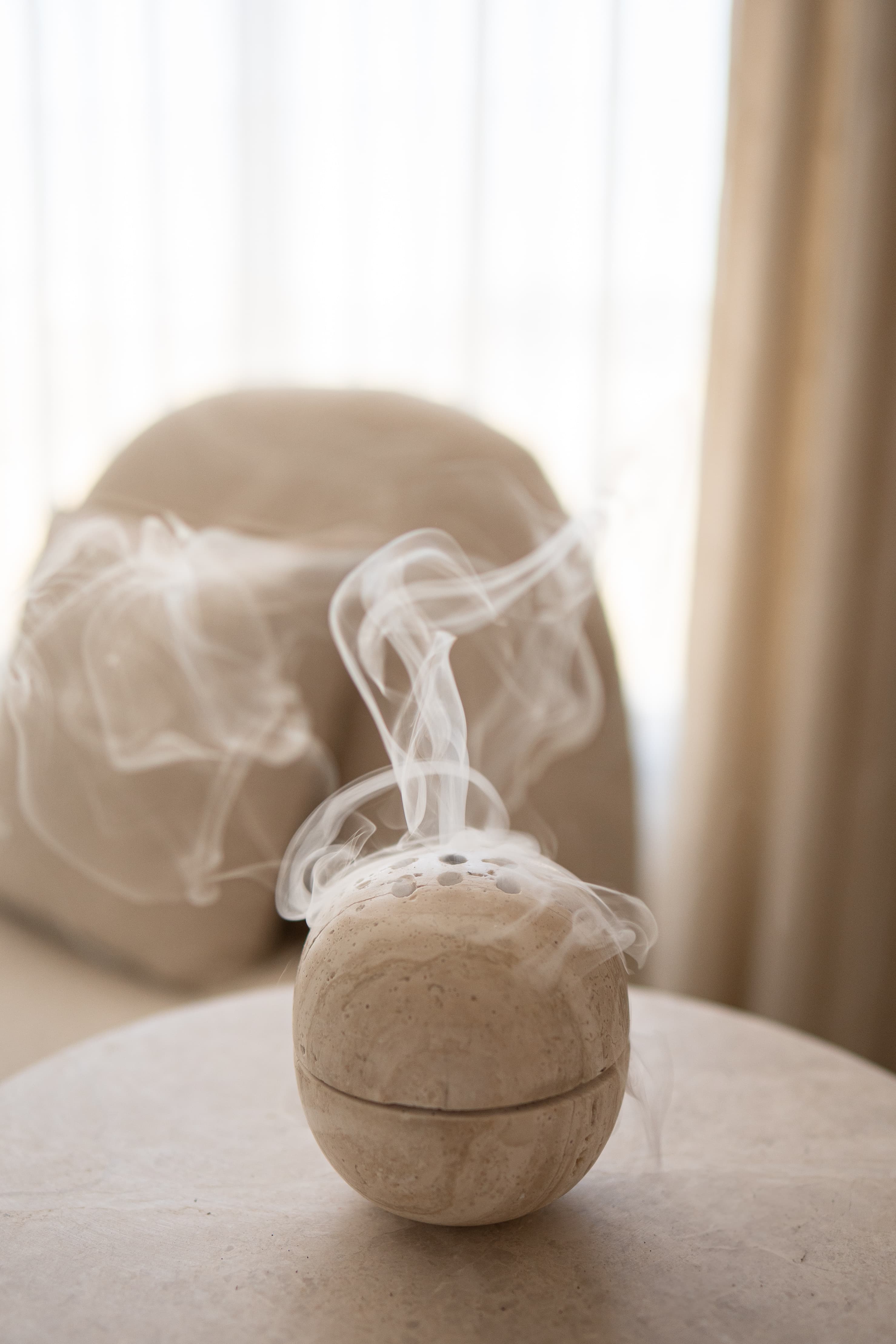 Smoke rising from a sculptural marble incense diffuser